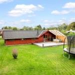 Rotes Haus mit Terrasse, Grill und Trampolin im Garten.