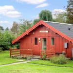 Rotes Holzhaus mit Garten und Holzbank vor der Tür.