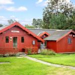 Rote Holzhütten mit Veranda und Grünfläche im Wald