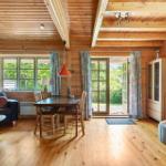 Holzvertäfelte Wohnung mit Essbereich, Sofa und TV. Durchgang zur Terrasse.