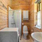 Badezimmer mit Dusche, Toilette, Waschbecken und Waschmaschine.