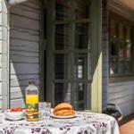 Tisch mit Frühstück auf der Terrasse vor einem Haus mit Holzfassade.