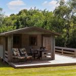 Holzhütte mit Terrasse, Gartenmöbeln und Blick auf Bäume.