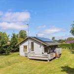 Haus mit Terrasse, Solaranlage und Garten unter blauem Himmel.