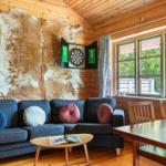 Wohnzimmer mit Sofa, Tisch und Dartboard an Holzwand
