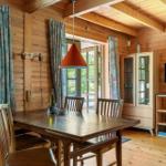 Esszimmer mit Holztisch, Stühlen und Fensterblick. Wanduhr, TV und Schrank sind vorhanden.