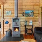 Kaminofen mit Flamme, Sofa, Wandbilder und Holzwände im Wohnbereich.