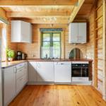 Küche mit Holzwand, weißen Schränken und Küchengeräten.