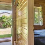 Schlafzimmer mit Holzwand, Bett und Fenster mit Blumenvorhang.