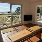 Wohnzimmer mit Blick auf Wasser, Holztisch und Fernseher an der Wand.