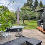 Terrasse mit Tisch, Stühlen und Schirm neben einem Holzhaus im Garten.