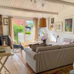 Wohnzimmer mit Sofa, Stühlen und Fenster zur Terrasse.