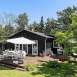 Schwarzes Haus mit Terrasse, weißer Sonnenschutz und Garten.