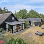 Schwarzes Haus mit Holzfassade und Glasveranda. Garten mit Liegestühlen und Tisch.
