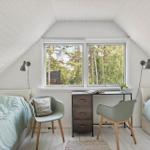 Zimmer mit zwei Betten, Schreibtisch und Fenster mit Blick auf Wald.