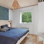 Schlafzimmer mit Bett, Fenster und Stuhl. Holzdecke und Wandverkleidung.