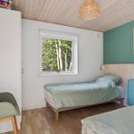 Schlafzimmer mit zwei Betten, Fenster mit Waldblick und blauem Schrank.