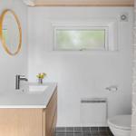 Badezimmer mit Waschbecken, Spiegel, Toilette und Dusche.