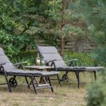 Zwei Liegestühle mit Tisch im Garten. Eine Flasche und ein Glas stehen darauf.