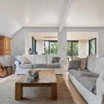 Wohnzimmer mit zwei Sofas, Holztisch und Gitarre. Durchgänge zu weiteren Räumen.