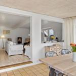 Essbereich mit Holztisch und Stühlen. Wohnzimmer mit Sofa und Kamin. Holzdecke und Boden.