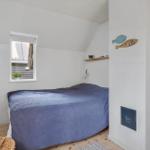 Schlafzimmer mit Bett, Fenster und Holzstuhl.