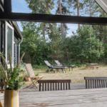 Terrasse mit Tisch und Stühlen, Blick auf Garten mit Liegen und Picknicktisch.