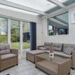 Wohnbereich mit Sitzgruppe, Glas-Tisch und Blick auf Garten.