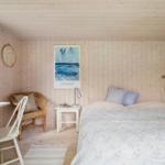 Schlafzimmer mit Bett, Nachttisch, Stuhl und Fenster.
