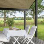 Terrasse mit Tisch, Stühlen und Blick auf grünes Feld