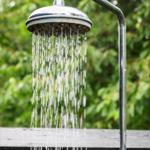 Außendusche mit Wasserstrahl und grüner Hintergrund