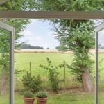Durch offene Fensterblick auf grünes Feld und Baum.