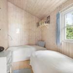 Zimmer mit zwei Betten, Holzwand und Fenster mit blauen Vorhängen.