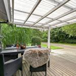 Terrasse mit Tisch, Stühlen und Felldecke unter Dach