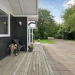 Holzterrasse neben Haus mit Sitzgelegenheit und Blick auf grünen Garten.