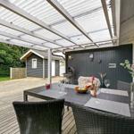 Terrasse mit Tisch, Stühlen und Grill unter Dach