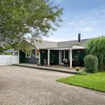 Haus mit Terrasse, Grill und Garten. Weiße Veranda mit Tisch und Stühlen.