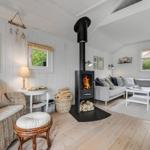 Wohnzimmer mit Kamin, Sofa und Sitzgelegenheiten. Holzboden und weiße Wände.
