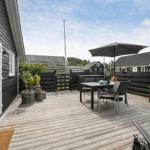 Terrasse mit Tisch, Stühlen und Sonnenschirm. Holzdeck und Gartenmöbel sichtbar.