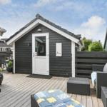 Schwarzes Holzhaus mit weißer Tür und Terrasse mit Gartenmöbeln.