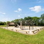 Kinderspielplatz mit Sandkasten, Klettergerüst und Rutsche auf grünem Rasen.