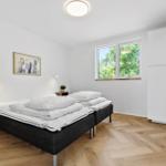 Schlafzimmer mit Doppelbett, Fenster und Holzboden.