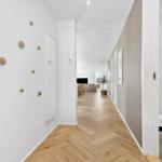 Flur mit Holzboden und Wanddekoration. Blick in Wohn- und Badezimmer.