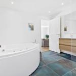 Bad mit Whirlpool, Waschtisch und Spiegel. Durchgang zur Wohnfläche.