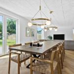 Essbereich mit langem Holztisch und Stühlen. Große Fenster mit Blick auf Garten.