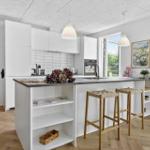 Moderne Küche mit weißem Schrank und Kücheninsel mit Sitzgelegenheit.