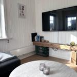 Wohnzimmer mit Fernseher, Holzbank und runder Tisch