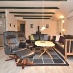 Wohnbereich mit Ledersofa, Sessel und Esstisch auf Teppich