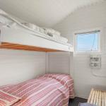 Zimmer mit Doppelstockbett, Fenster und Bambusbank.