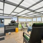 Terrasse mit Sitzgruppe, Grill und Tisch unter Dach